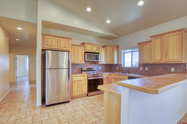 2038 Park Ave, Pagosa Springs, CO 81147 - kitchen featuring appliances with stainless steel finishes, a sink, a peninsula, backsplash, and lofted ceiling
