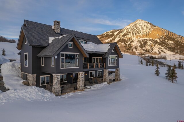 905 County Road 317, Crested Butte, CO 81224 - snow covered property with a balcony, a chimney, and stone siding