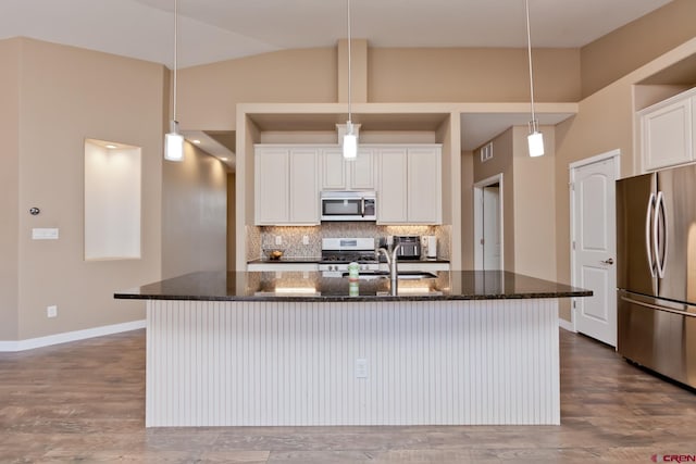 2488 Josefine Ln, Grand Junction, CO 81505 - kitchen featuring stainless steel appliances, decorative backsplash, dark stone counters, a kitchen island with sink, and wood finished floors
