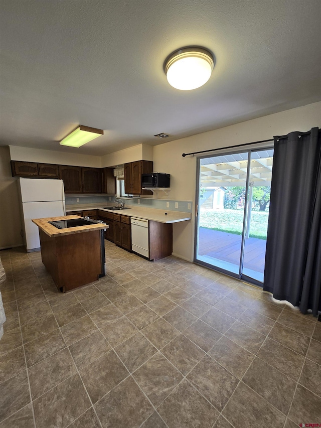 608 Alameda Dr, Cortez, CO 81321 - kitchen featuring white appliances, dark brown cabinetry, a sink, light countertops, and a center island