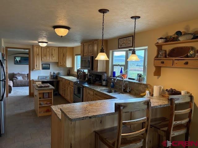 250 Pashuta Dr, Gunnison, CO 81230 - kitchen with open shelves, a sink, stainless steel appliances, a peninsula, and decorative light fixtures
