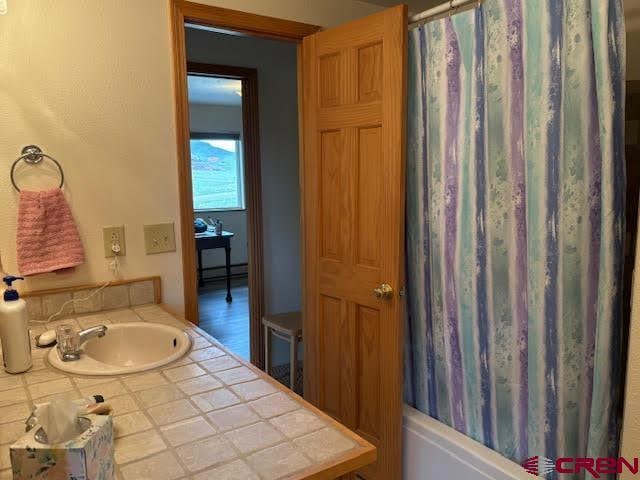 250 Pashuta Dr, Gunnison, CO 81230 - bathroom featuring baseboard heating, shower / bathtub combination with curtain, and vanity