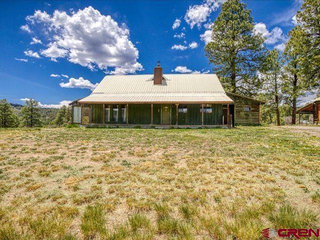 157 S Primrose Ridge Pl, Pagosa Springs, CO 81147 - back of property with a chimney, a lawn, a sunroom, and metal roof