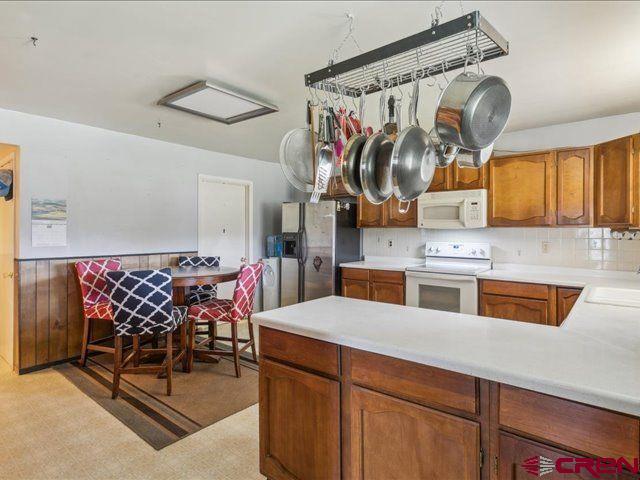 157 S Primrose Ridge Pl, Pagosa Springs, CO 81147 - kitchen with white appliances, light countertops, a sink, light flooring, and brown cabinetry