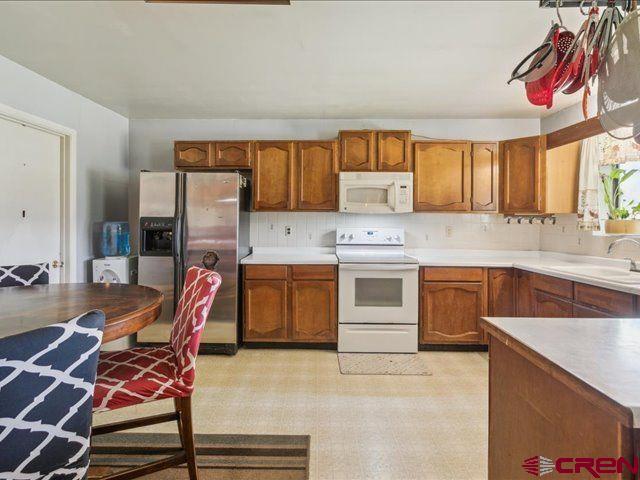 157 S Primrose Ridge Pl, Pagosa Springs, CO 81147 - kitchen featuring white appliances, a sink, brown cabinets, light floors, and tasteful backsplash