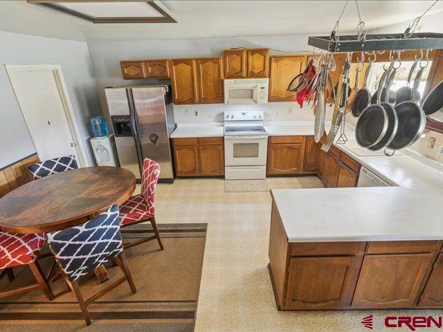 157 S Primrose Ridge Pl, Pagosa Springs, CO 81147 - kitchen with white appliances, brown cabinets, light countertops, and light flooring