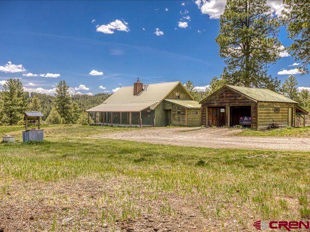 157 S Primrose Ridge Pl, Pagosa Springs, CO 81147 - view of front of property with a detached garage, an outdoor structure, a front yard, a chimney, and a pole building