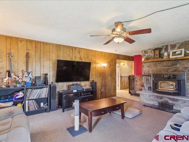 157 S Primrose Ridge Pl, Pagosa Springs, CO 81147 - carpeted living area with a ceiling fan, wood walls, a wood stove, and a textured ceiling