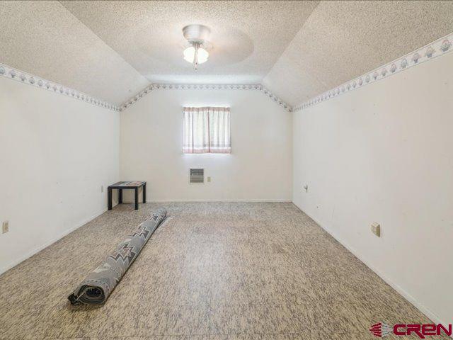 157 S Primrose Ridge Pl, Pagosa Springs, CO 81147 - additional living space featuring vaulted ceiling, carpet floors, and a textured ceiling