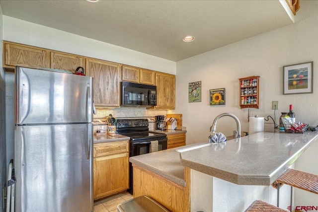 88 W Peregrine Cir Unit 4Unit 1, Pagosa Springs, CO 81147 - kitchen featuring black appliances, a peninsula, a breakfast bar area, backsplash, and light tile patterned floors