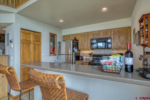 88 W Peregrine Cir Unit 4Unit 1, Pagosa Springs, CO 81147 - kitchen with black appliances, tasteful backsplash, brown cabinets, a peninsula, and recessed lighting