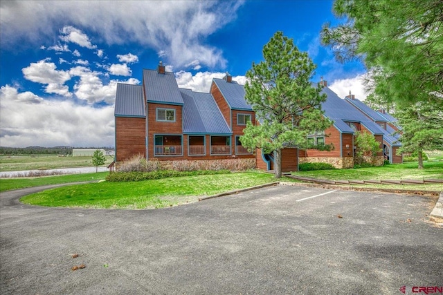 88 W Peregrine Cir Unit 4Unit 1, Pagosa Springs, CO 81147 - view of front facade featuring a chimney, uncovered parking, a front lawn, stone siding, and metal roof