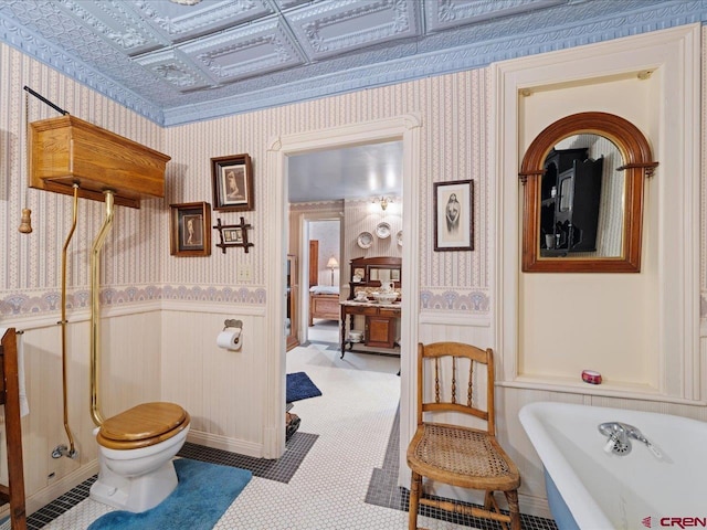 445 4th St, Ouray, CO 81427 - full bath with wallpapered walls, a soaking tub, wainscoting, toilet, and an ornate ceiling