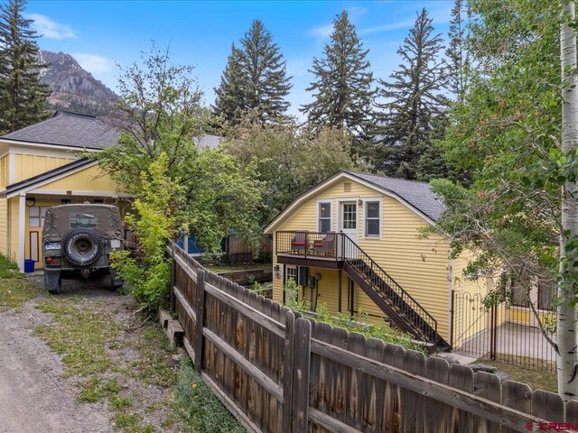445 4th St, Ouray, CO 81427 - rear view of property featuring roof with shingles, stairway, a deck, a fenced backyard, and driveway