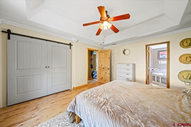 2224 American Way, Montrose, CO 81401 - bedroom with a raised ceiling, wood finished floors, a barn door, ornamental molding, and a closet