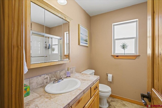 2224 American Way, Montrose, CO 81401 - bathroom featuring toilet, vanity, a shower with door, baseboards, and tile patterned flooring