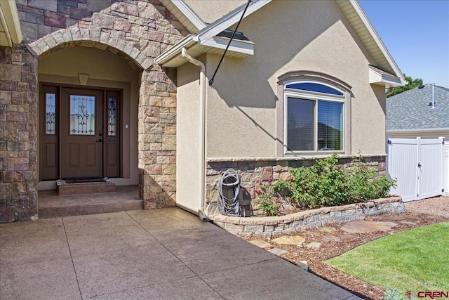 2224 American Way, Montrose, CO 81401 - doorway to property featuring stone siding, stucco siding, and a gate