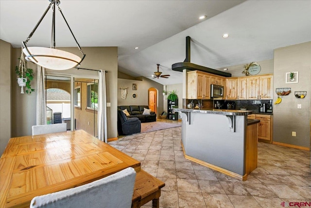 2224 American Way, Montrose, CO 81401 - kitchen featuring stainless steel microwave, a kitchen breakfast bar, dark countertops, lofted ceiling, and a peninsula