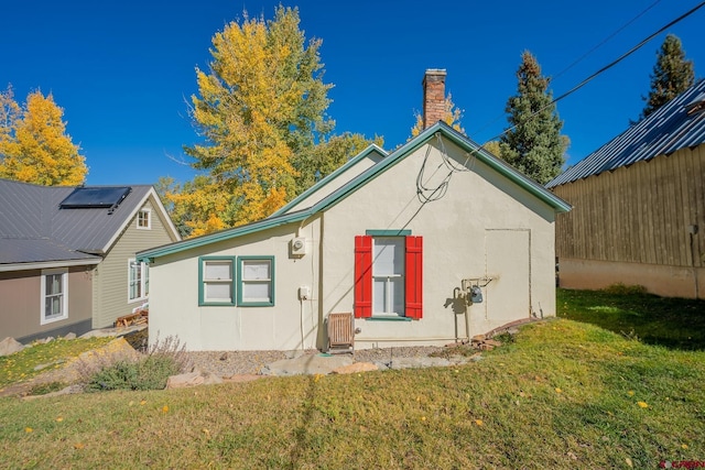 418 Elk Ave, Crested Butte, CO 81224 - view of side of home featuring stucco siding, a lawn, and a chimney