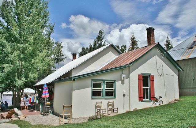 418 Elk Ave, Crested Butte, CO 81224 - back of house featuring a chimney, a yard, and stucco siding