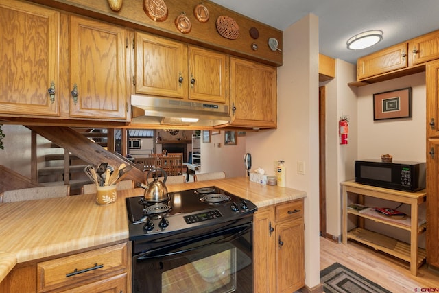 15 Marcellina Ln # 120, Mount Crested Butte, CO 81225 - kitchen featuring black appliances, under cabinet range hood, light wood finished floors, light countertops, and brown cabinets