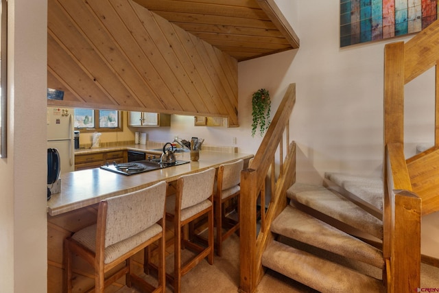 15 Marcellina Ln # 120, Mount Crested Butte, CO 81225 - kitchen with black appliances, light carpet, wooden ceiling, a sink, and a breakfast bar
