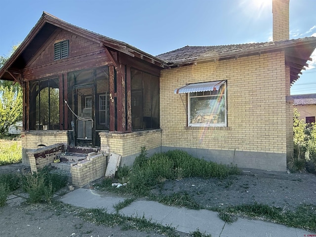 840 Hastings St, Delta, CO 81416 - view of property exterior featuring brick siding, a sunroom, and a chimney