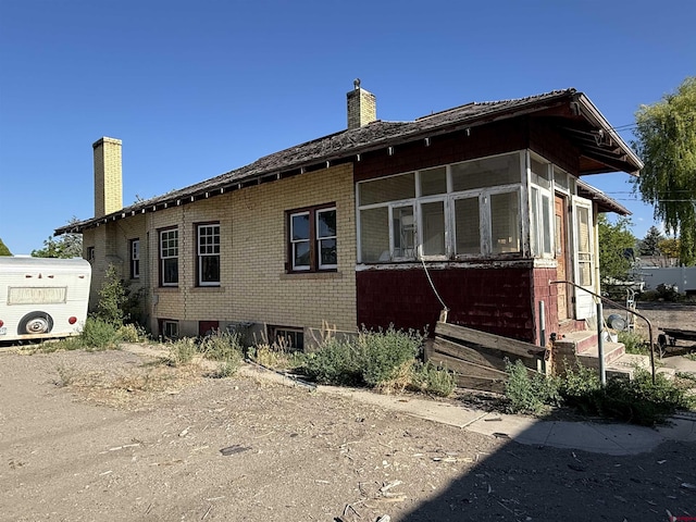 840 Hastings St, Delta, CO 81416 - view of side of property with a chimney, entry steps, a sunroom, and brick siding
