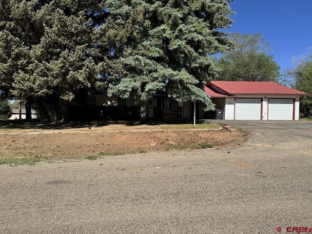 1010 N Dove St, Dove Creek, CO 81324 - view of front of home featuring asphalt driveway, an attached garage, and metal roof