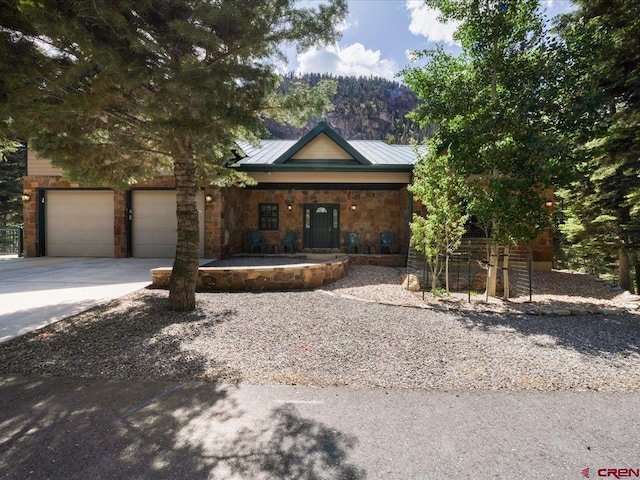 112 Ouray Vista Ln, Ouray, CO 81427 - view of front of property featuring stone siding, concrete driveway, covered porch, a garage, and a mountain view