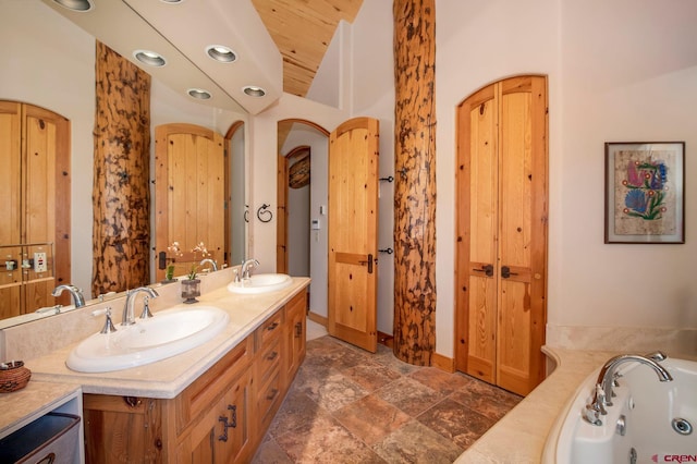 536 Journeys End Rd, Crested Butte, CO 81224 - bathroom with double vanity, a tub with jets, vaulted ceiling, baseboards, and recessed lighting