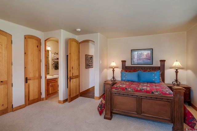 536 Journeys End Rd, Crested Butte, CO 81224 - bedroom featuring light carpet, baseboards, connected bathroom, and arched walkways