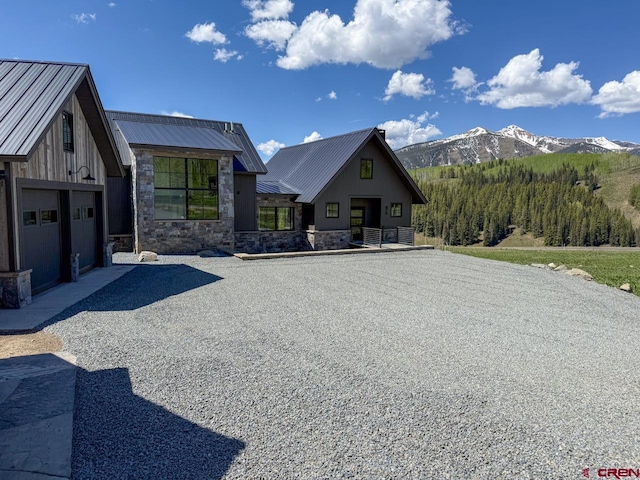 470 Meadow Dr, Crested Butte, CO 81224 - view of front of house with stone siding, a mountain view, metal roof, and driveway
