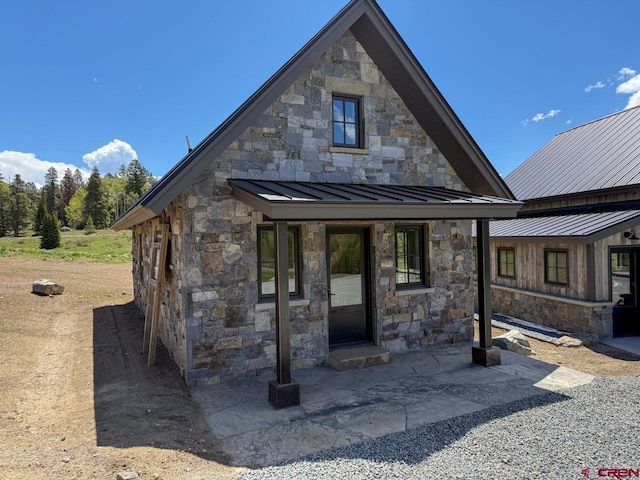 470 Meadow Dr, Crested Butte, CO 81224 - view of front of home with a standing seam roof, stone siding, metal roof, and a patio