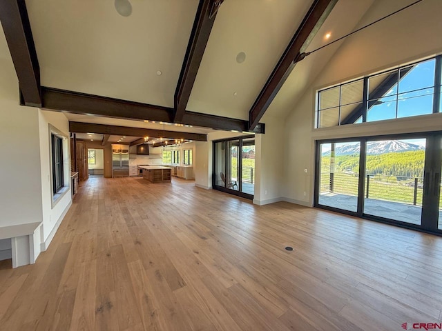 470 Meadow Dr, Crested Butte, CO 81224 - unfurnished living room featuring high vaulted ceiling, beam ceiling, light wood-type flooring, baseboards, and a chandelier