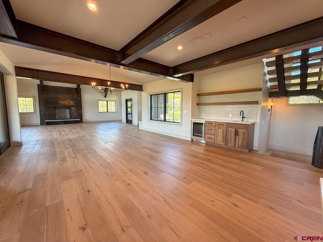 470 Meadow Dr, Crested Butte, CO 81224 - unfurnished living room featuring wine cooler, a chandelier, light wood finished floors, beamed ceiling, and baseboards