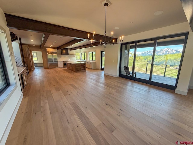 470 Meadow Dr, Crested Butte, CO 81224 - unfurnished living room with a chandelier, light wood finished floors, beamed ceiling, baseboards, and a mountain view