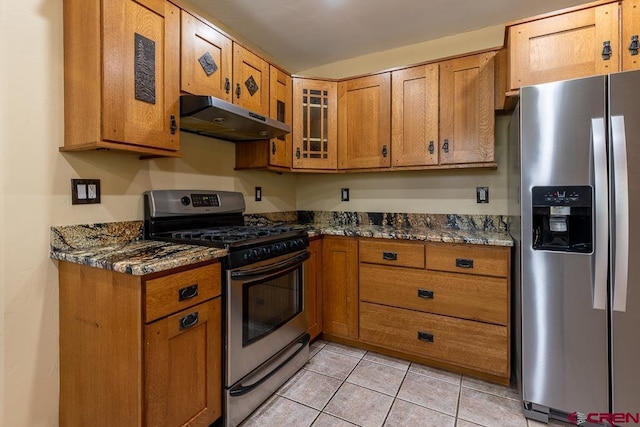 30 Stagecoach Rd, Bayfield, CO 81122 - kitchen featuring stainless steel appliances, under cabinet range hood, brown cabinetry, light tile patterned flooring, and dark stone countertops
