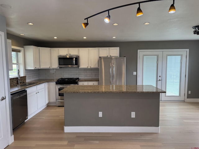 445 Saddle Cir, Pagosa Springs, CO 81147 - kitchen with appliances with stainless steel finishes, a sink, a center island, decorative backsplash, and white cabinets
