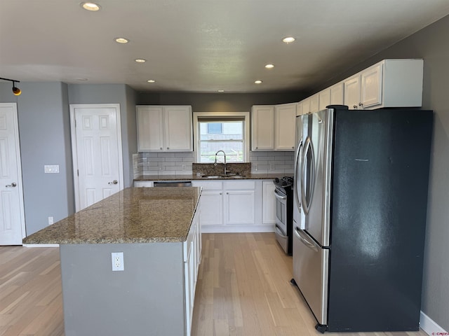 445 Saddle Cir, Pagosa Springs, CO 81147 - kitchen with stainless steel appliances, a sink, light wood-type flooring, dark stone counters, and decorative backsplash