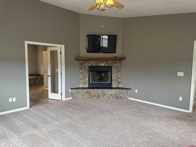 445 Saddle Cir, Pagosa Springs, CO 81147 - unfurnished living room featuring carpet flooring, baseboards, ceiling fan, a fireplace, and a towering ceiling