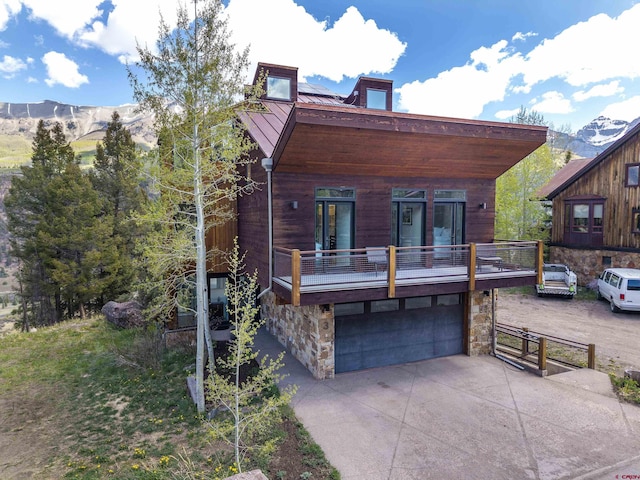 123 Boulders Way, Mountain Village, CO 81435 - view of front of property with a garage, stone siding, concrete driveway, metal roof, and a standing seam roof