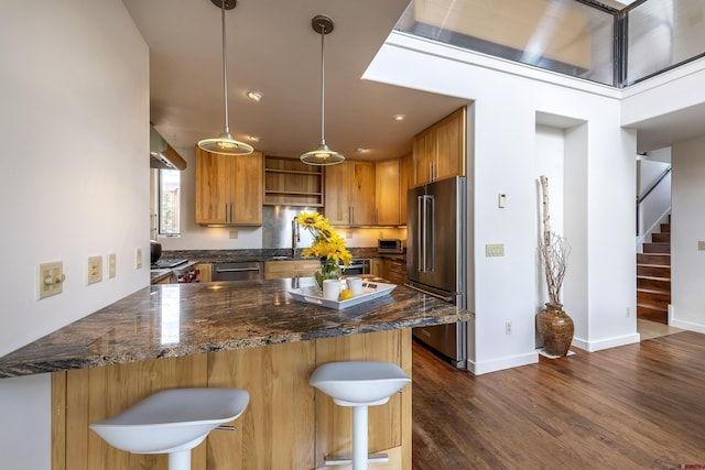 123 Boulders Way, Mountain Village, CO 81435 - kitchen featuring appliances with stainless steel finishes, open shelves, a peninsula, dark wood-style floors, and a breakfast bar
