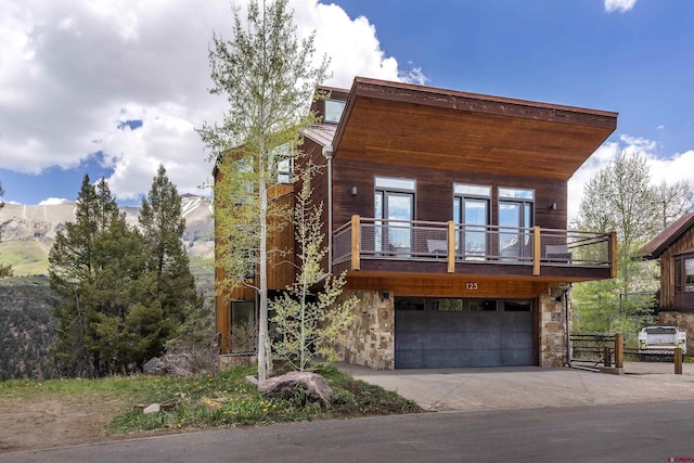 123 Boulders Way, Mountain Village, CO 81435 - contemporary house featuring a garage, stone siding, driveway, a balcony, and metal roof