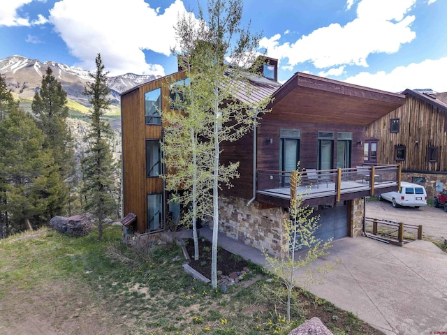 123 Boulders Way, Mountain Village, CO 81435 - view of front of property featuring stone siding, driveway, a mountain view, a garage, and a balcony