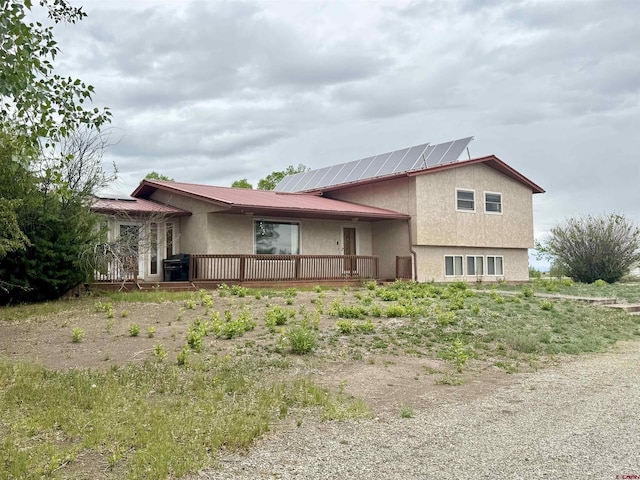 6645 Gaumer Ln, Alamosa, CO 81101 - view of front of house with stucco siding, roof mounted solar panels, a deck, and metal roof