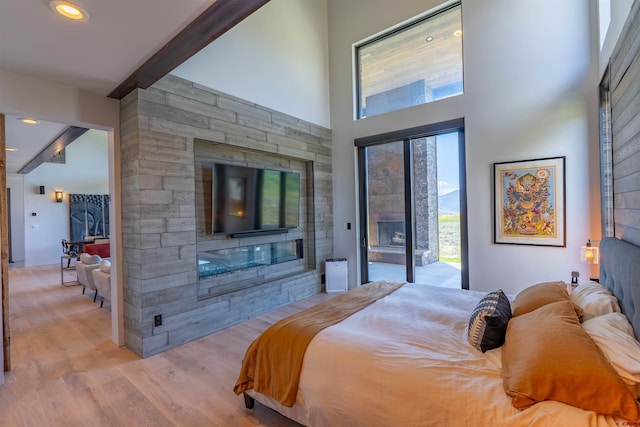 470 White Stallion Cir, Crested Butte, CO 81224 - bedroom featuring beamed ceiling, access to outside, light wood-style floors, a stone fireplace, and a high ceiling