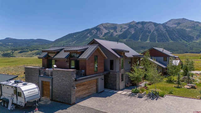 470 White Stallion Cir, Crested Butte, CO 81224 - view of front facade with a standing seam roof, a mountain view, stone siding, an attached garage, and a balcony