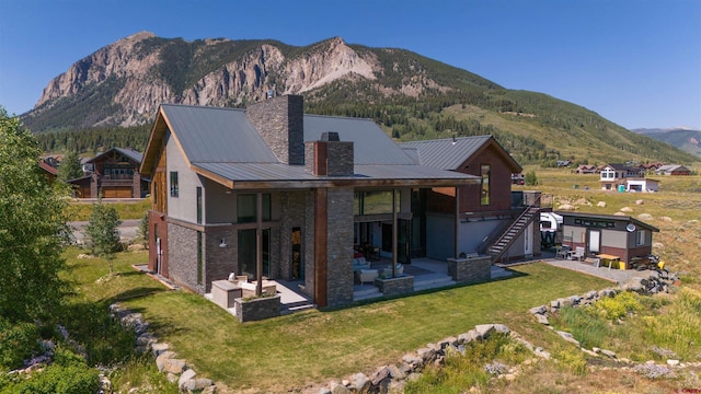 470 White Stallion Cir, Crested Butte, CO 81224 - rear view of house with a patio area, a mountain view, a chimney, stairs, and a lawn