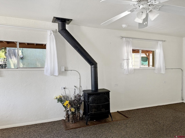135 N 4th St, Hotchkiss, CO 81419 - detailed view of a wood stove, carpet, a ceiling fan, baseboards, and a smoke detector